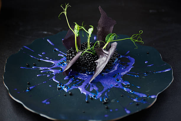 Risotto with cuttlefish ink and black caviar Plate with black risotto on black background with dramatic side light. Haute cuisine. calamari photos stock pictures, royalty-free photos & images