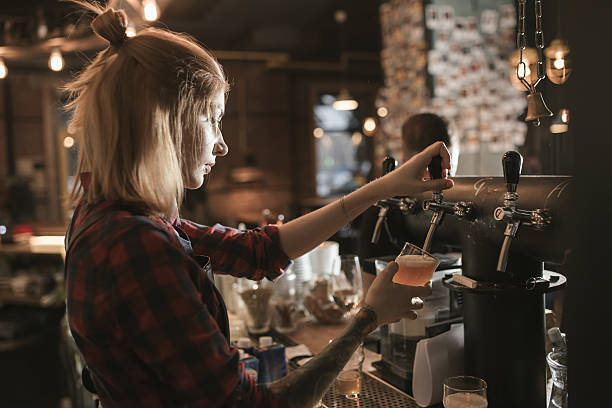 Female bartender pouring beer from tap at bar Female bartender pouring beer from tap at bar pub bar counter bar men stock pictures, royalty-free photos & images