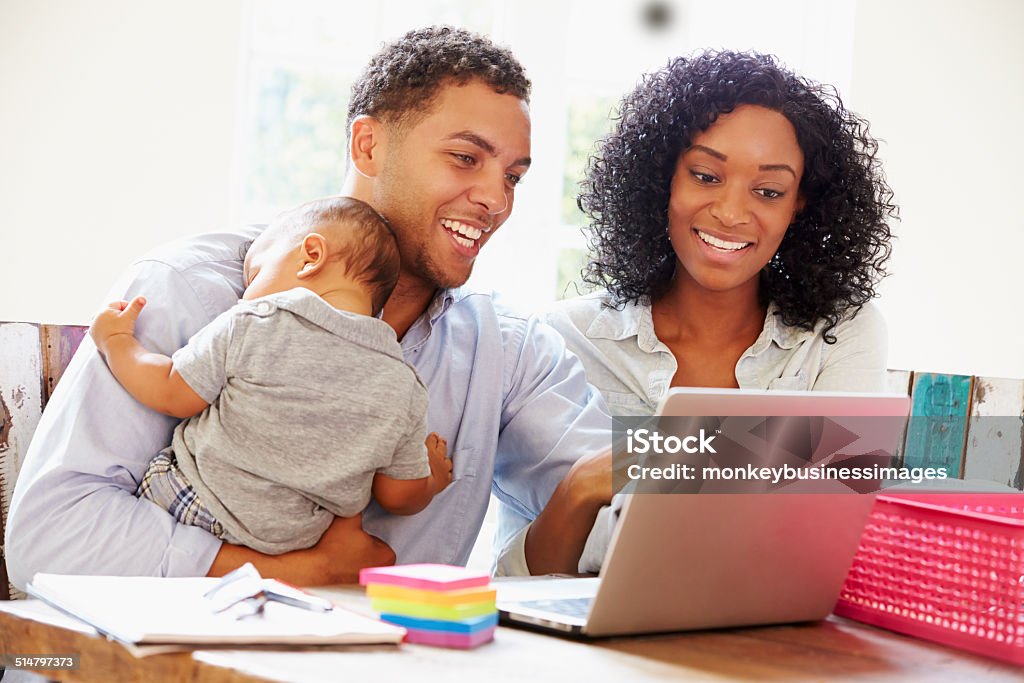 Parents With Baby Working In Office At Home Parents With Baby Working In Office At Home Looking At Laptop Smiling Family Stock Photo