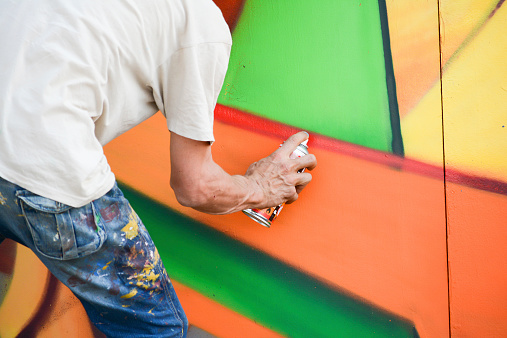 young artist painting a wall in the middle of the day