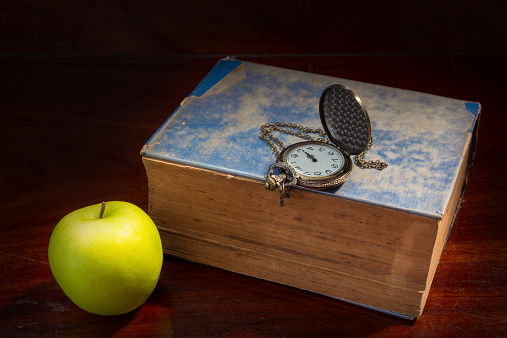 Green apple with antique book and watch.