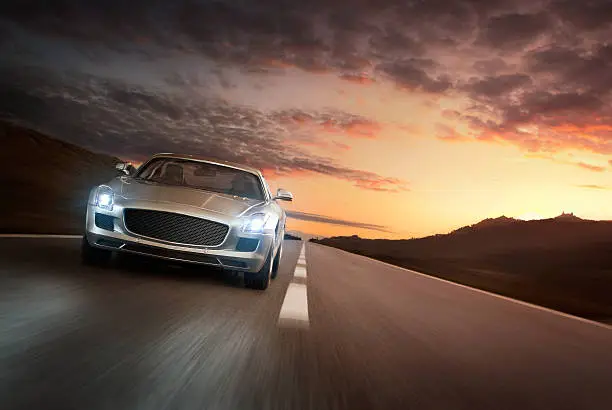 Luxury sports car speeding on a highway at the sunset