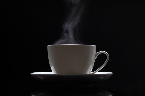 Cup of black coffee with steam on the black background