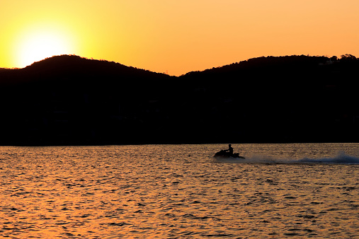 Silhouette of a mountain and a jet ski on a lake by the sunset