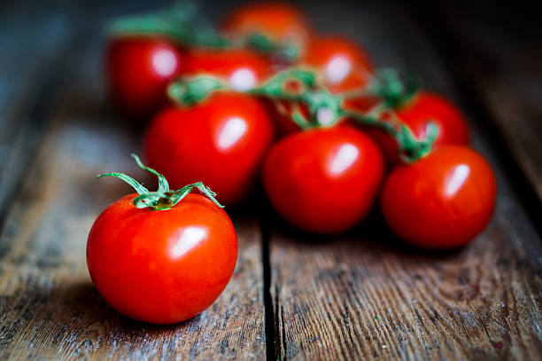 istock Tomatoes on the vine on rustic wooden background 514825866