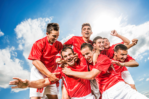 Cheerful soccer team celebrating their success against the sky.   