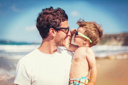 Father and son on the beach wearing sunglasses