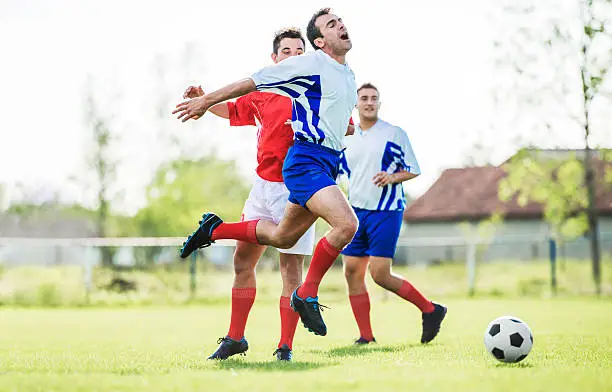 Soccer player makes a foul on his opponent.  