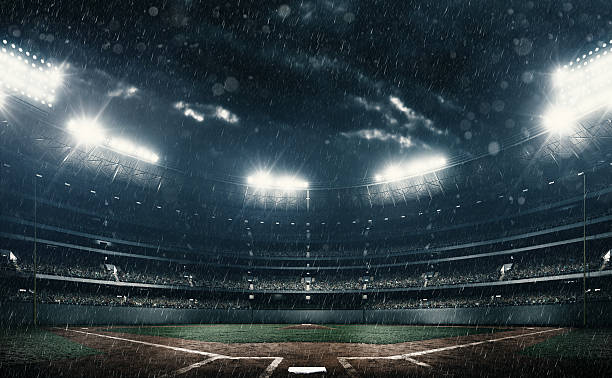 Baseball stadium A wide angle of a outdoor baseball stadium full of spectators under a stormy sky at night. It is raining there. The image has depth of field with the focus on the foreground part of the pitch. baseball diamond photos stock pictures, royalty-free photos & images