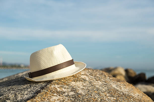 Selective focus on white vintage hat on the rock at the beach