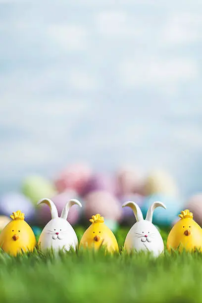 Little Easter critters sitting in grass with Easter egg background