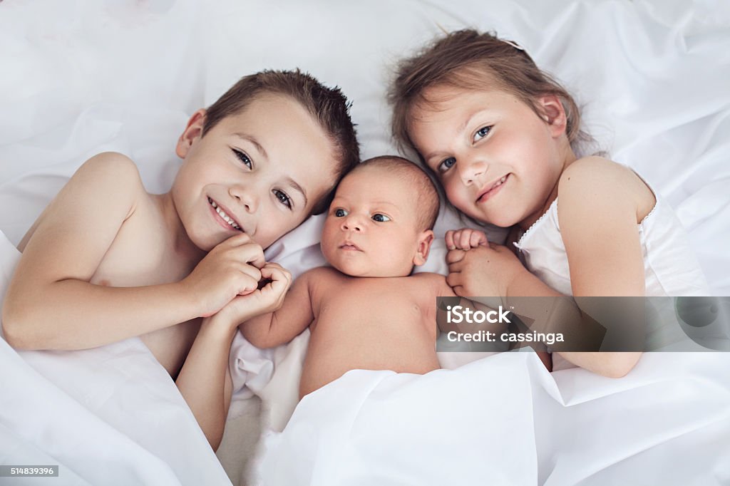 Happy family Three cheerful kids at home, newborn baby with brother and sister, happy family, love and friendship concept Sibling Stock Photo