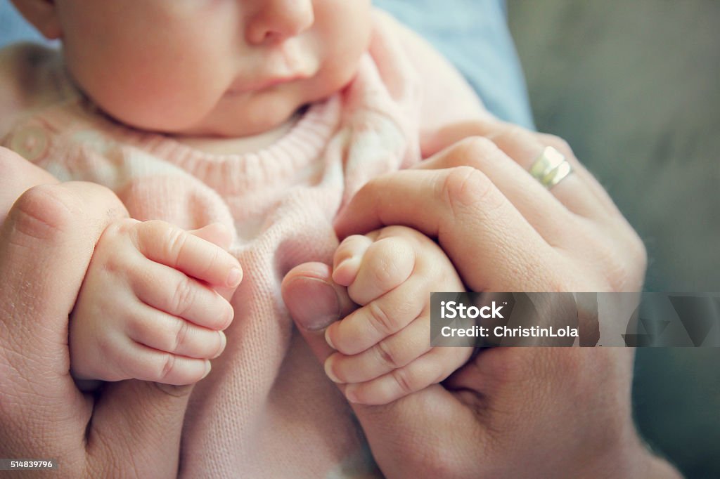 Newborn Baby Girls Hands Holding Fathers Fingers Focus on the hands of a 3 month old baby girl holding the fingers of her father.  Vintage style color filter. Baby - Human Age Stock Photo