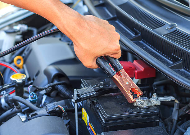 istock car mechanic uses battery jumper cables to charge dead batte 514850748