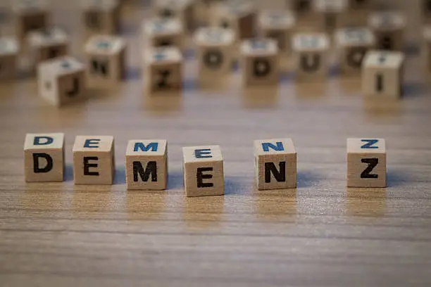 Demenz (German Dementia) written in wooden cubes on a table from well ordered to chaotic