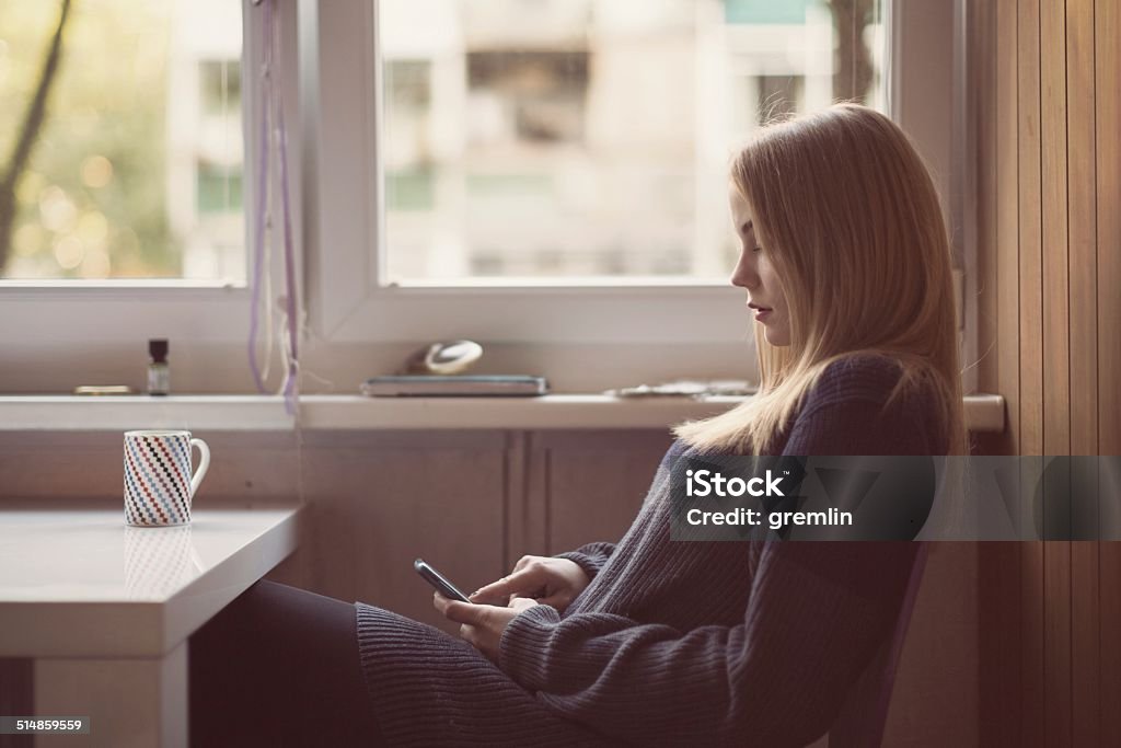 Young woman text messaging in the kitchen Young woman text messaging in the kitchen. Mobile Phone Stock Photo