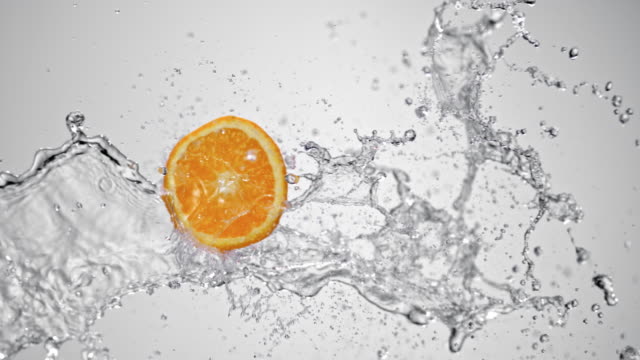 SLO MO Slice of orange in a water splash on white background