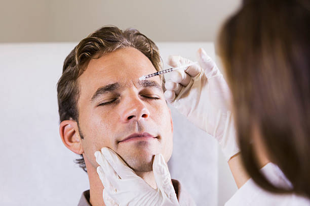 Man getting botulinum toxin Mid adult man (30s) receiving botulinum toxin injection. forehead photos stock pictures, royalty-free photos & images