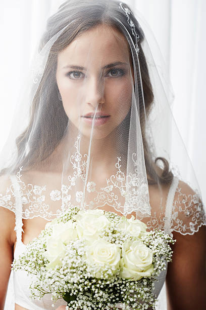 istock Serious young bride in veil holding bouquet 514911669
