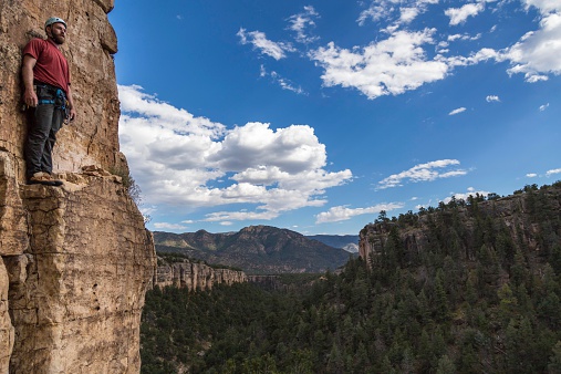 A rock climber stands with his back against the cliff looking over a steep canyon near Canon City, Colorado