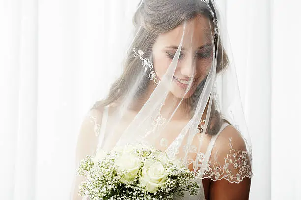 Excited young bride in veil holding bouquet