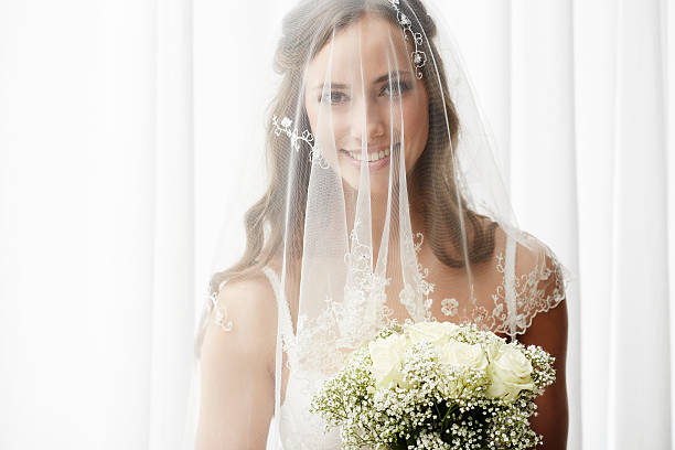 istock Excited young bride in veil holding bouquet, portrait 514912091