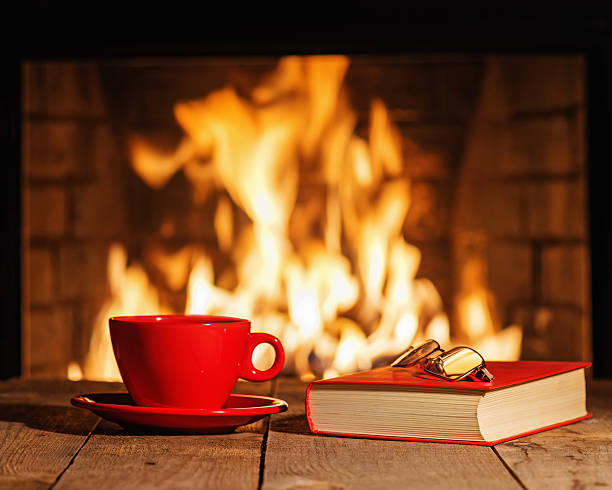 istock Red cup, glasses and old book near fireplace. 514915668