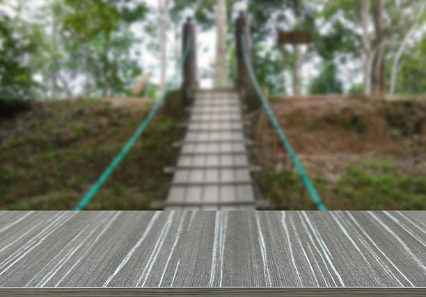 empty wooden table with view from the middle of pedestrian rope bridge across valley blur background for displaying your product
