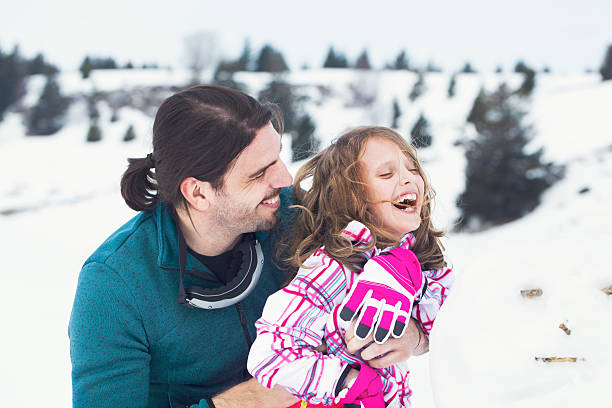 Father hugs his daughter affectionately in the snow