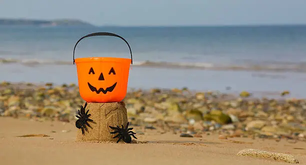 Photo of Halloween pumpkin beach bucket on a sandcastle