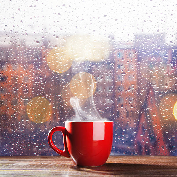 Steaming cup of coffee Steaming cup of coffee over a cityscape background rainy cafe stock pictures, royalty-free photos & images
