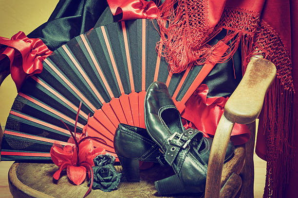 Flamenco clothing on a wooden chair Clothing for Flamenco dance. Black shoes, fan, red scarf with tassels and paper roses are lying on a vintage wooden chair. Edited as a vintage photo with dark edges. flamenco dancing photos stock pictures, royalty-free photos & images