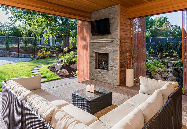 Covered patio exterior behind new luxury home Covered patio with fireplace, tv, and couch, with view of lush green grass and landscaping patio stock pictures, royalty-free photos & images