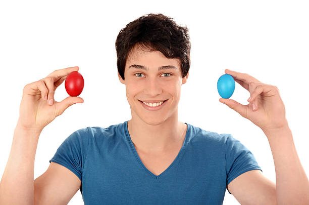 istock Happy young man holding up red and blue Easter eggs. 514934031