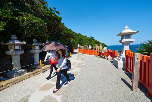 Nichinan, Japan - September 26, 2014: two young japanese woman walking in the Udo-jingu taoist shrine. They carry umbrella to protect them from the sun light.