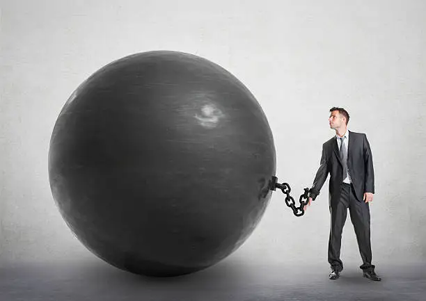 Businessman chained to a large ball