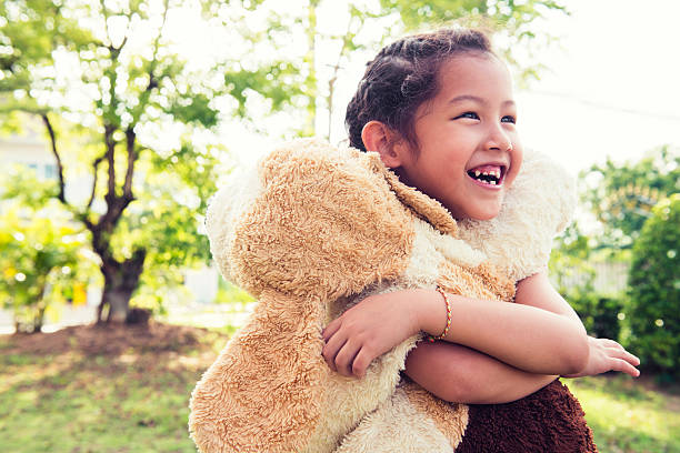 幸せなタイの女性彼女のぬいぐるみの包み - embracing smiling gap children only ストックフォトと画像