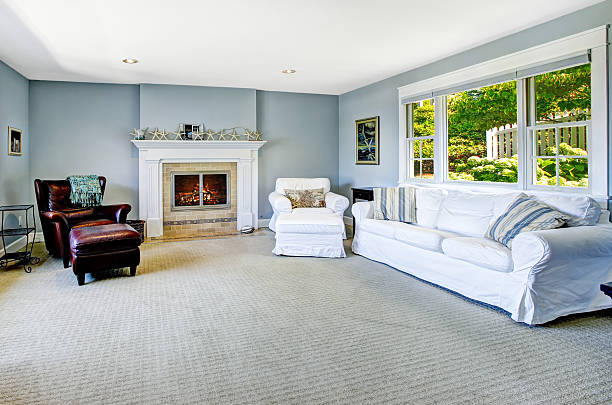 Light blue living room with white sofa, armchair and leather chair and cozy fireplace