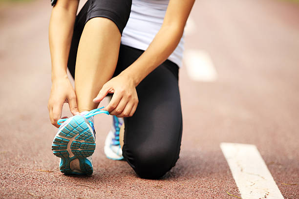istock woman runner  tying shoelaces on trail 514965947