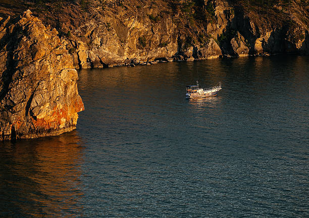 bateau près de rochers au coucher de soleil sur le lac baïkal - sibiria photos et images de collection