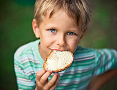 Little boy eating loaf of bread with butter