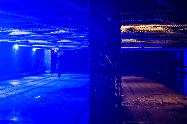 Bridge in Camden with blue light to deter drug users London, UK - October 29, 2015: Underneath a railway bridge in Camden, North London, crossing the Regent's Canal. The blue light is designed to deter intravenous drugs users, by making it hard for them to locate veins for injection. A man is walking in the background deter stock pictures, royalty-free photos & images