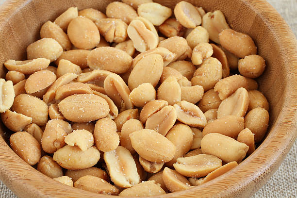 istock Salted roasted peanuts in bamboo bowl on rough linen cloth 514986146