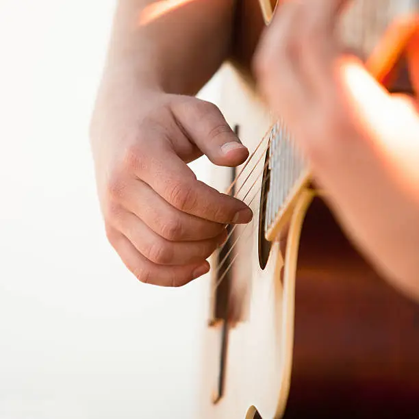 Photo of Man's hand on the strings of the guitar