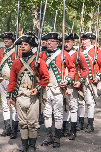 Wheaton, IL, USA - September 13, 2014: Unidentified men dressed as British soldiers stand at attention, muskets on left shoulders, before a mock battle at a reenactment of the American Revolutionary War (1775-1783).
