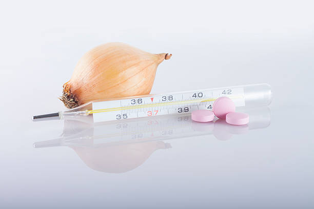 onions and pills with thermometer stock photo