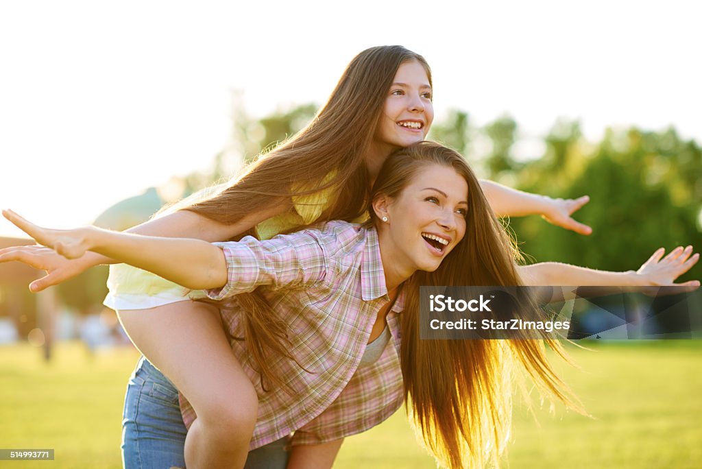 Having a carefree day at the park Shot of a beautiful young woman giving her daughter a piggyback ride at the parkhttp://www.azarubaika.com/iStockphoto/2014_07_01_MotherAndDother_OrSysters.JPG 14-15 Years Stock Photo