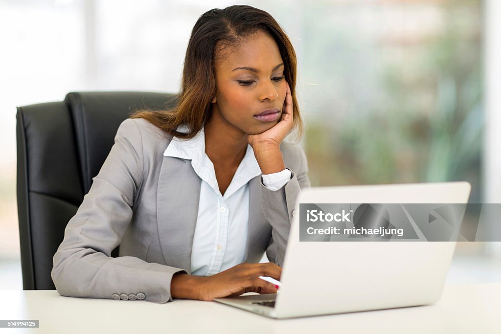 young african businesswoman looking at the laptop screen thoughtful young african businesswoman looking at the laptop screen Boredom Stock Photo