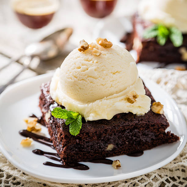 Chocolate brownie with vanilla ice cream, nuts and mint Chocolate brownie with vanilla ice cream, nuts and mint, served om white plate, rustic wood background homemade brownies with vanilla ice cream stock pictures, royalty-free photos & images