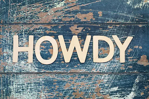 Photo of Word howdy written with wooden letters on rustic surface